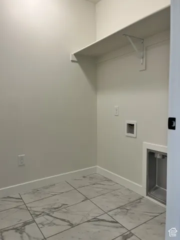 Built-in shelving, utility hookups, and a laundry basin complement the tile flooring