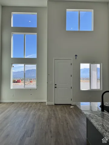 Two-story living area featuring tall windows, wood-finish flooring, and a kitchen island with a granite countertop