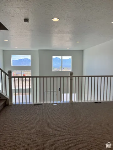 Carpeted open loft area with white baluster railing and recessed ceiling lighting