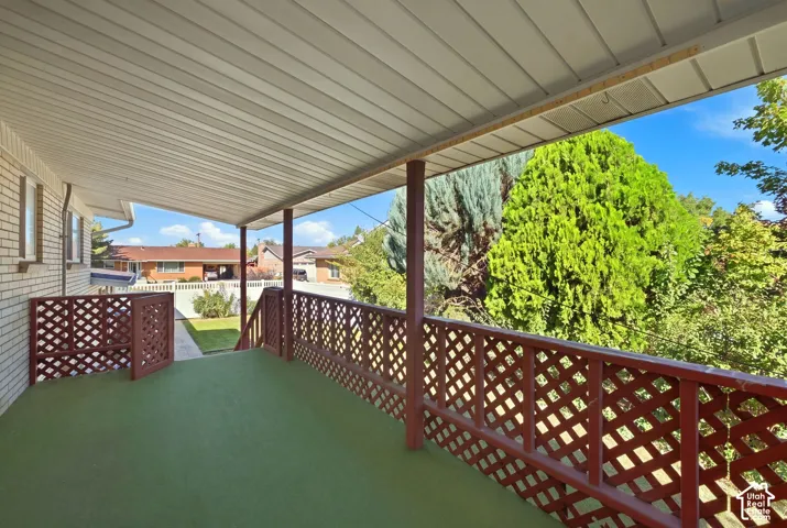 Covered outdoor living space featuring a latticed railing, support columns, and textured flooring