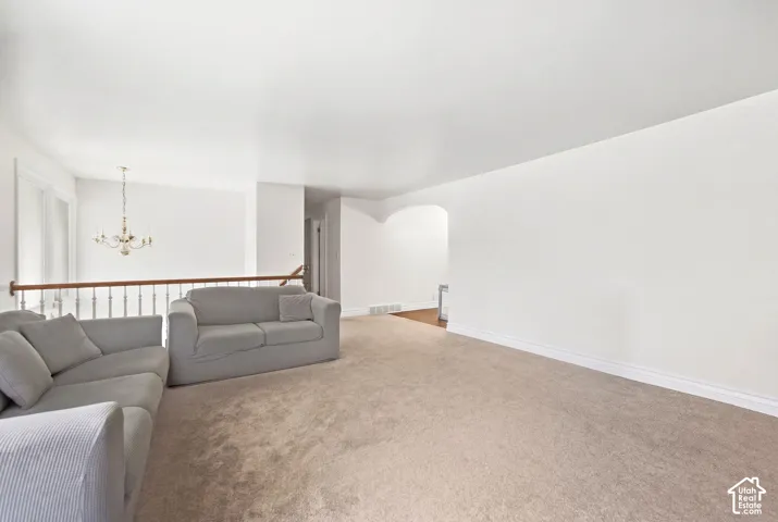 Expansive carpeted area with a white baluster railing and wood handrail