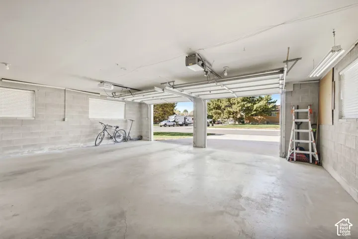 Two-car garage with concrete block walls, overhead garage door opener, and multiple windows