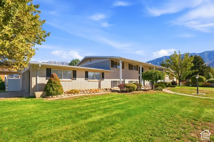 Brick exterior with a mature tree, an expansive lawn, and a paved walkway