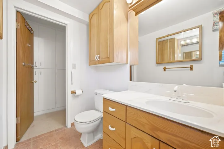 Bathroom featuring a wood-finish vanity with a white countertop and integrated sink, above-vanity cabinetry, and a mirrored medicine cabinet