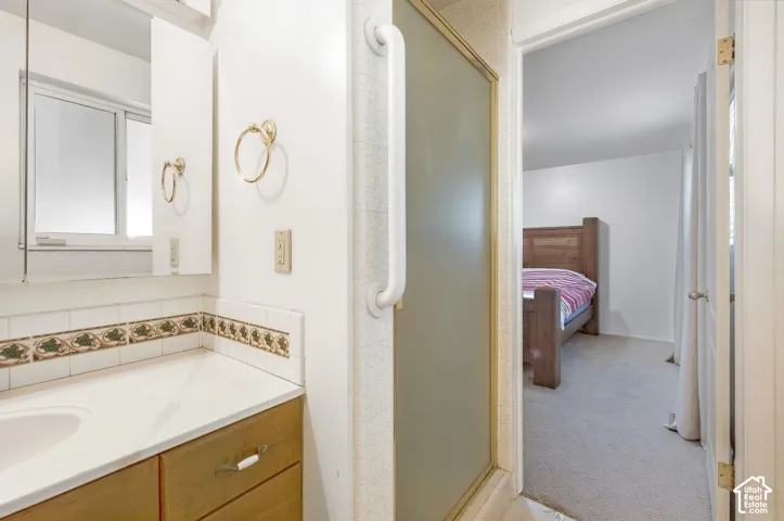 Bathroom vanity with integrated sink, wood-finish cabinetry, and decorative tile backsplash