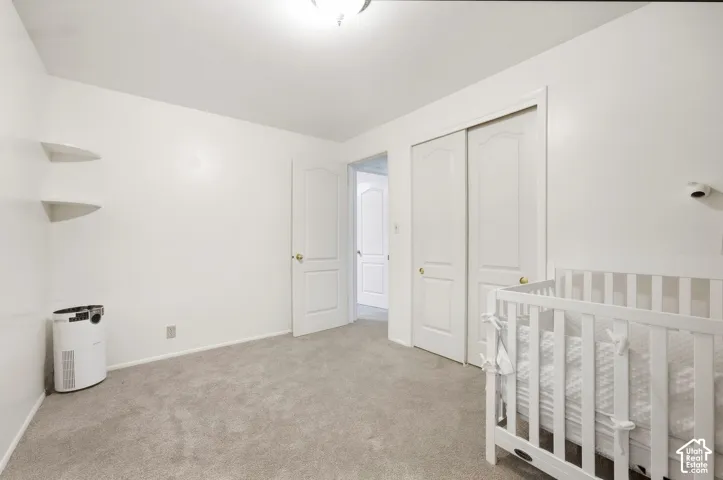 Wall-to-wall carpeting, white walls, built-in corner shelving, and closet with bi-fold doors