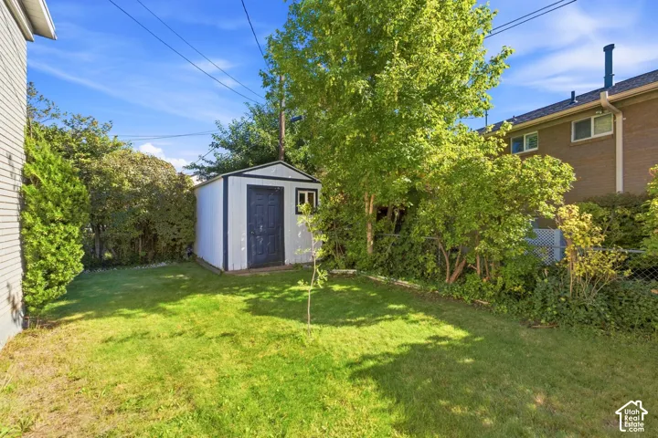 Expansive yard featuring a manicured lawn, established trees, and a utility shed with a window