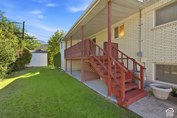 Expansive green lawn, brick exterior, covered patio, privacy lattice, and outdoor storage shed