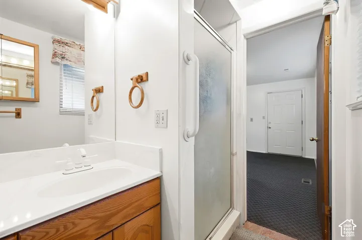 Vanity with white countertop and integrated sink, wood-finish cabinetry, and framed mirror with integrated lighting