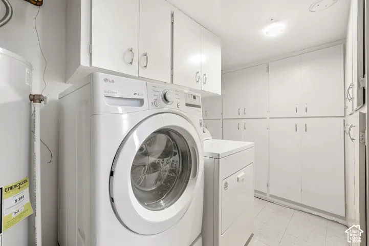 Laundry area featuring extensive white cabinetry, a built-in water heater, and a tiled floor