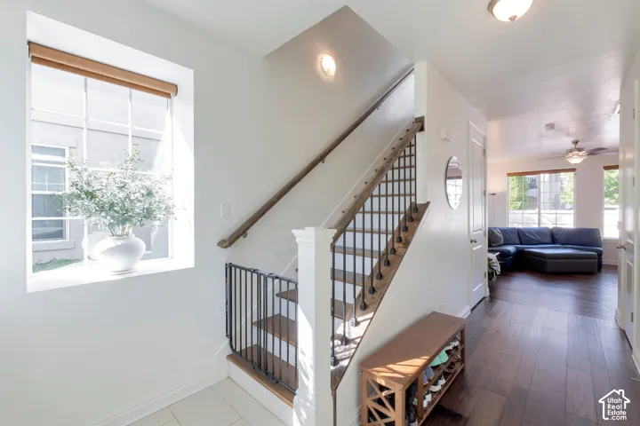 Hardwood flooring, wood staircase with metal balusters, and transom window
