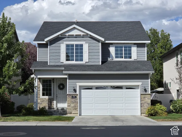 Gray siding with stone accents, a white garage door, and a covered entryway