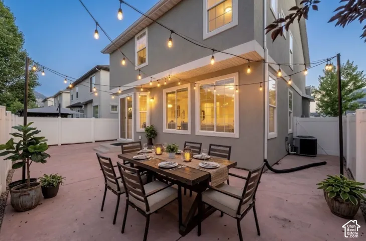 Expansive concrete patio area, privacy fencing, exterior lighting, multiple windows, and a sliding glass door