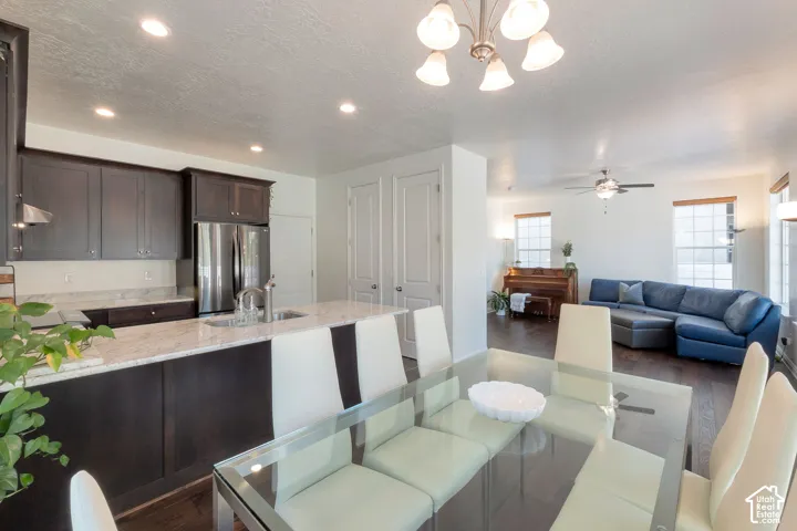 Kitchen island with a granite countertop, dark wood-finish cabinetry, stainless steel appliances, and recessed lighting