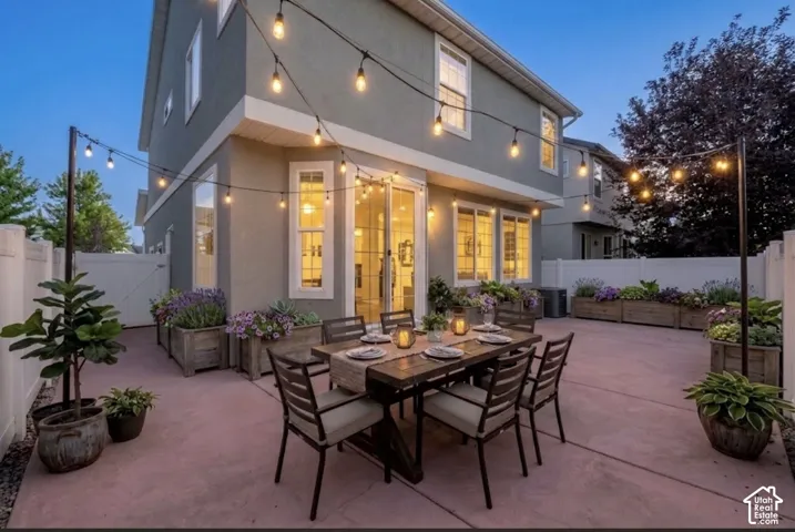 Poured concrete patio with string lighting, multiple planter boxes, and a sliding glass door