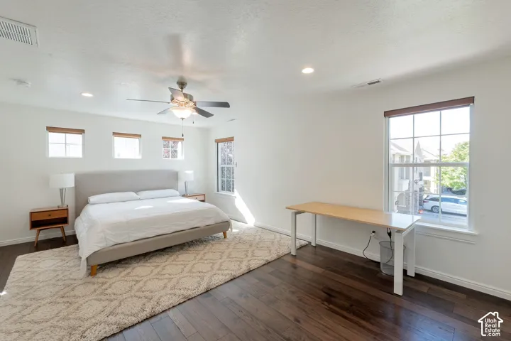 Dark wood-finish flooring, recessed lighting, ceiling fan, and multiple windows