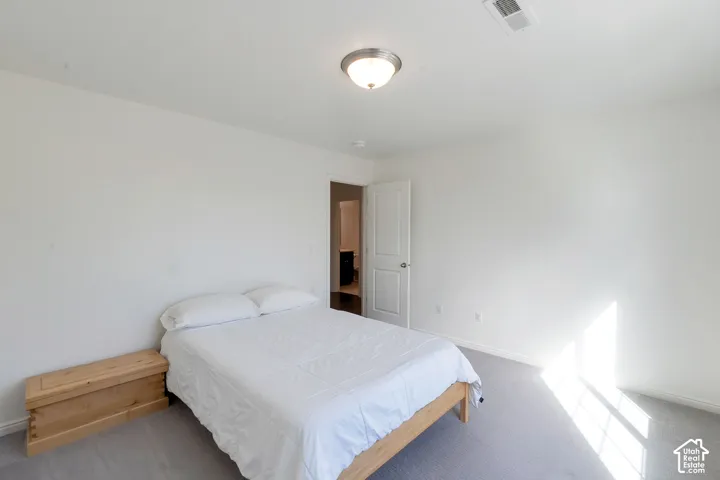 White walls complemented by gray carpet flooring and a ceiling-mounted light fixture