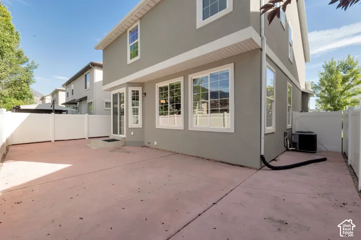 Paved patio area with a white privacy fence, multi-pane windows, and a glass-paneled entry door