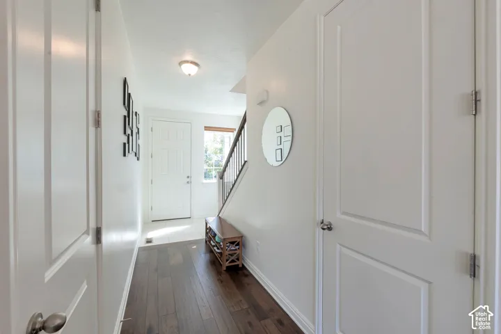 Wood-finish flooring, white paneled interior doors, and a staircase with dark wood-finish handrails