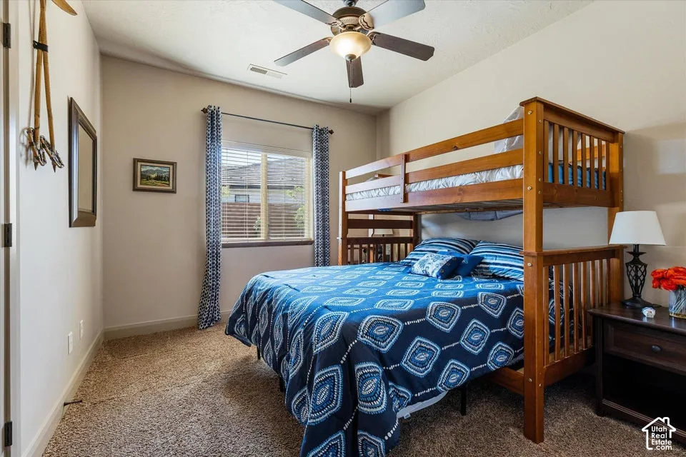 Carpeted room featuring a ceiling fan, a window with blinds and drapes, and a wood-frame bunk bed