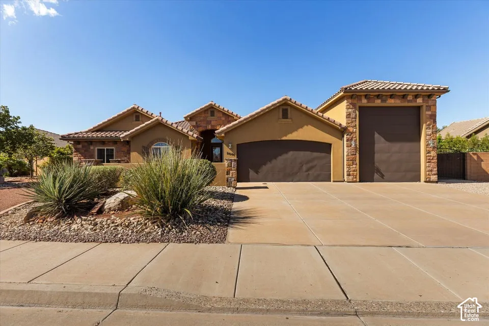 Stucco exterior with stone accents, tile roofing, and a paved driveway