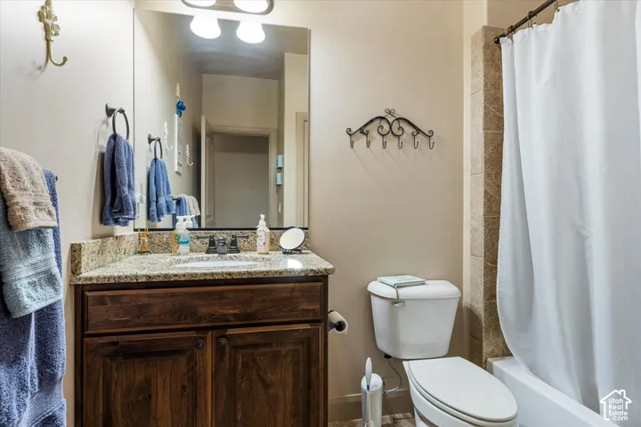 Granite-finish countertop with an undermount sink, wood-finish vanity with paneling, and a full-width mirror