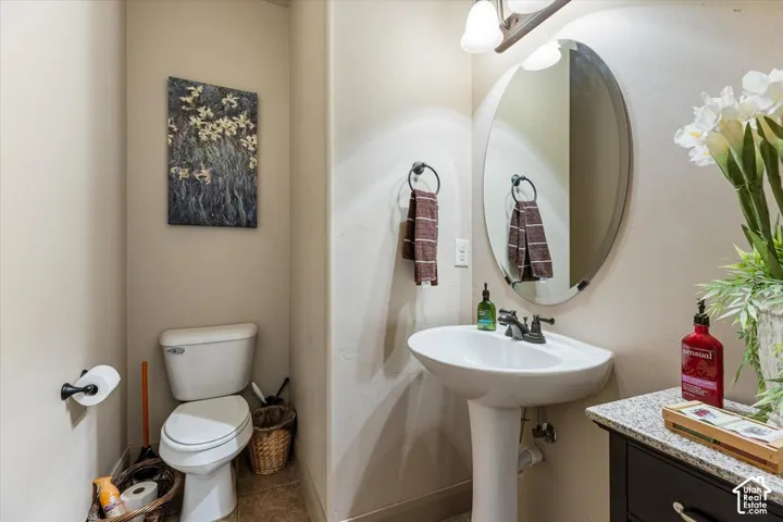 Pedestal sink with dark-toned faucet, wall-mounted mirror, and vanity lighting fixture