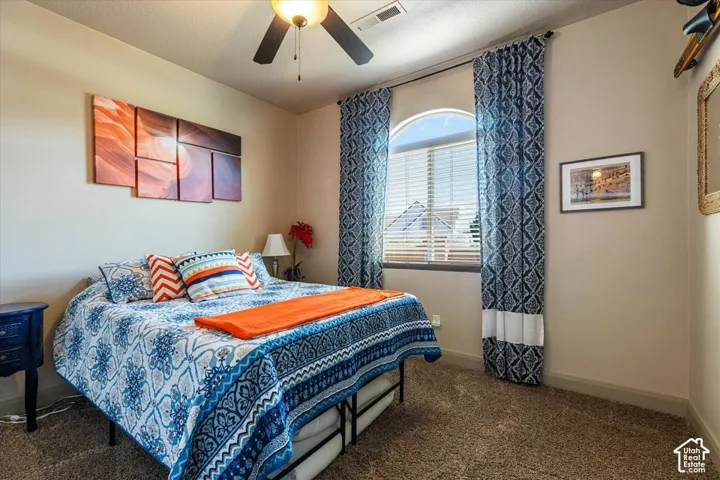 Arched window with blinds, ceiling fan with integrated lighting, and carpeted flooring