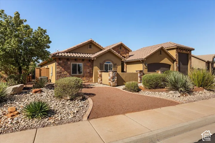 Stucco exterior with stone accents, tile roof, and a gravel driveway