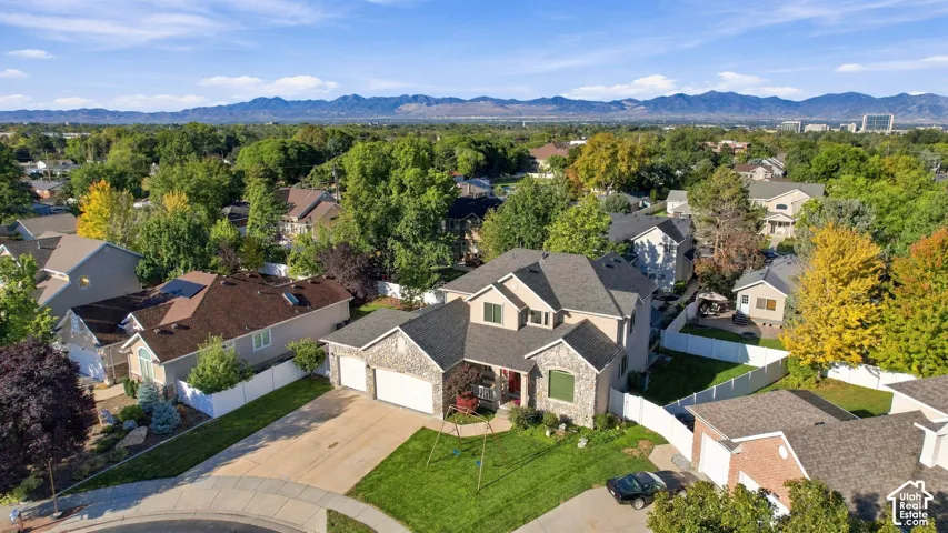 Stone and siding exterior with a two-car garage, mature landscaping, and a fenced backyard
