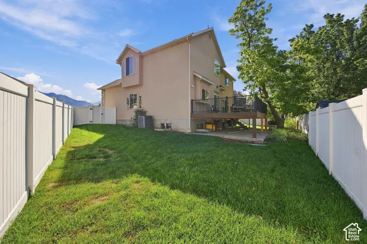 Spacious backyard with a grass lawn, privacy fencing, and a multi-level deck