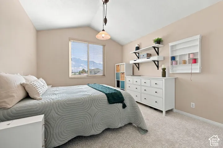 Vaulted ceiling, window with blinds, suspended light fixture, built-in wall shelving, and textured carpet flooring