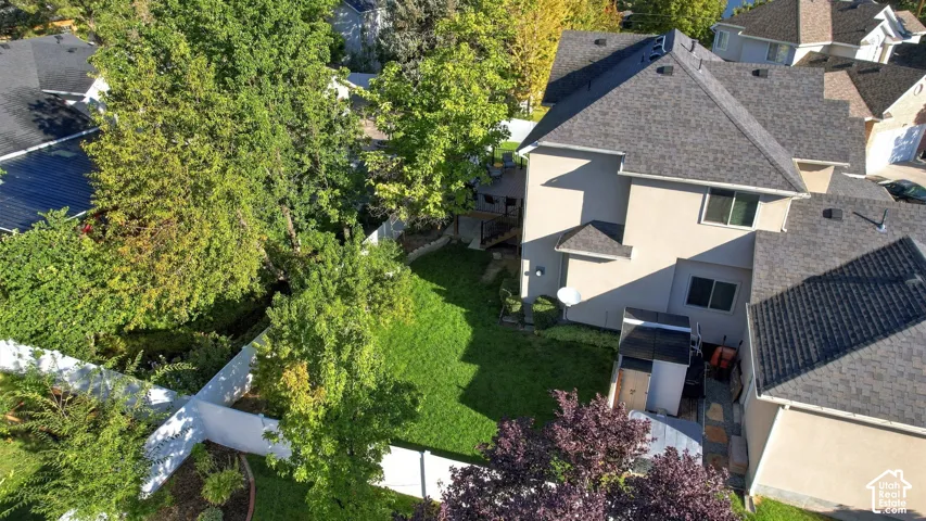Spacious backyard featuring a manicured lawn, established landscaping, and stucco exterior