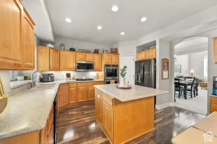 Spacious kitchen featuring wood cabinetry, stone-finish countertops, dark wood-finish flooring, a stainless steel microwave, and a dark stainless steel refrigerator