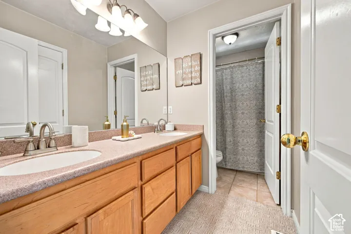 Vanity with dual integrated sinks, light wood-finish cabinetry, and an expansive wall-mounted mirror