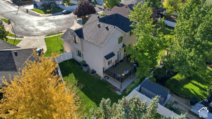 Backyard featuring a tiered deck, manicured lawn, and mature trees