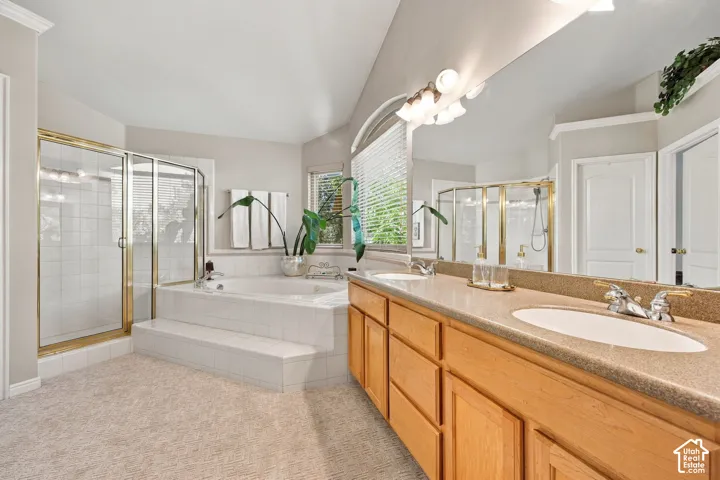 Dual vanity with light wood cabinetry and integrated sinks, a built-in jetted tub with tile surround, a separate shower with a glass enclosure, and a large wall-mounted mirror