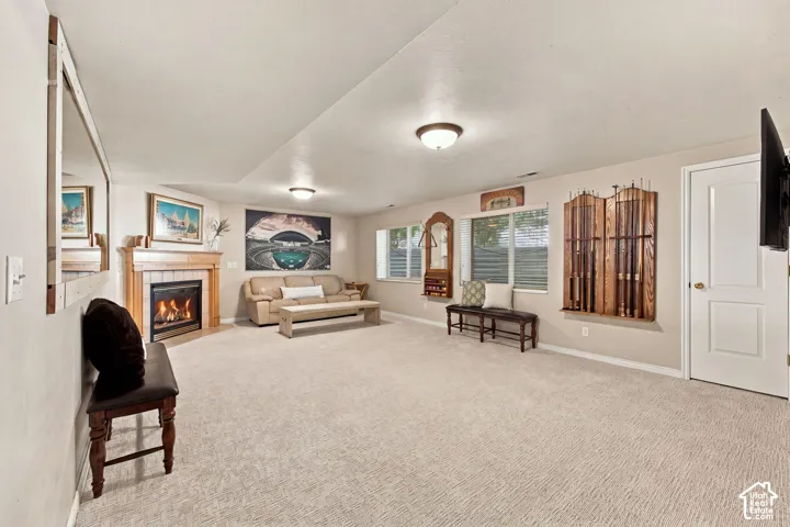 Spacious living area featuring light-toned carpeting, recessed lighting, multiple windows, and a built-in fireplace with a wood mantle