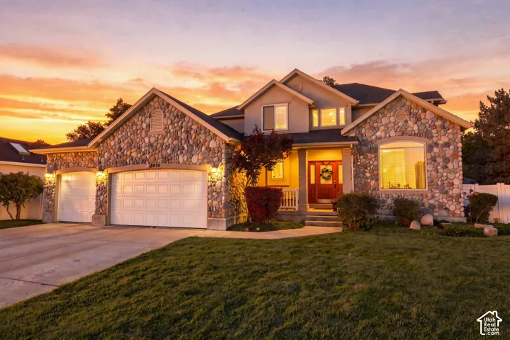 Stone facade exterior with a red entry door, an attached three-car garage, and a concrete driveway