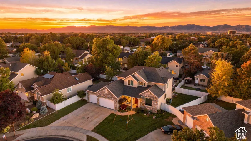 Two-story residence featuring a stone and siding exterior, multi-car driveway, attached garage, and mature landscaping