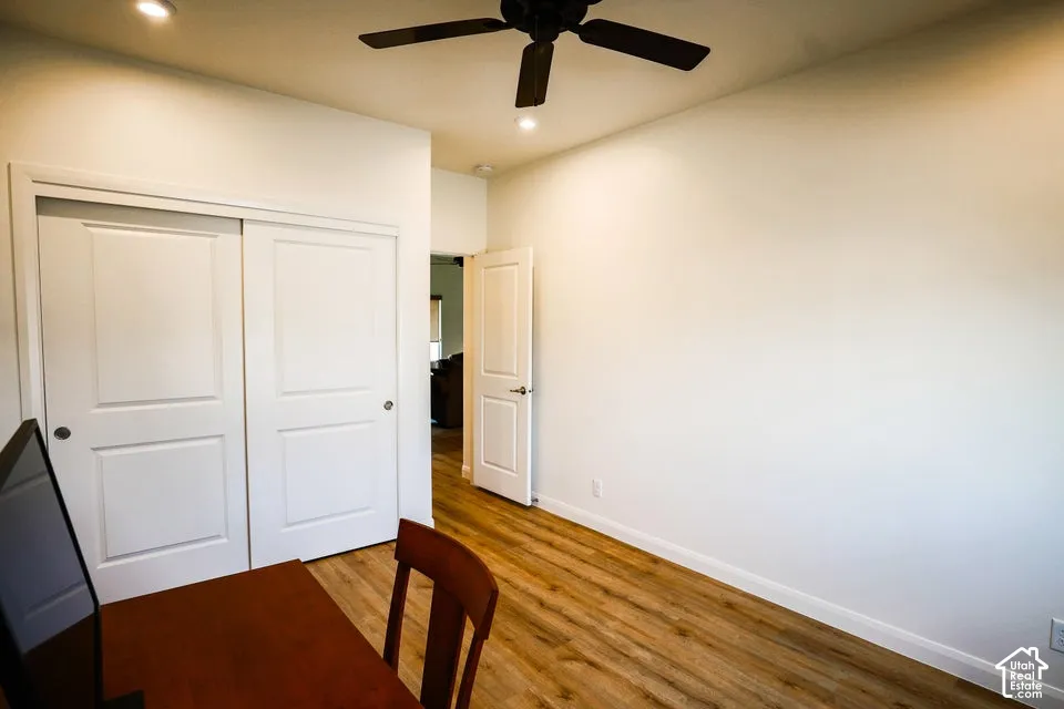 Wood-finish flooring, recessed lighting, ceiling fan, and white doors