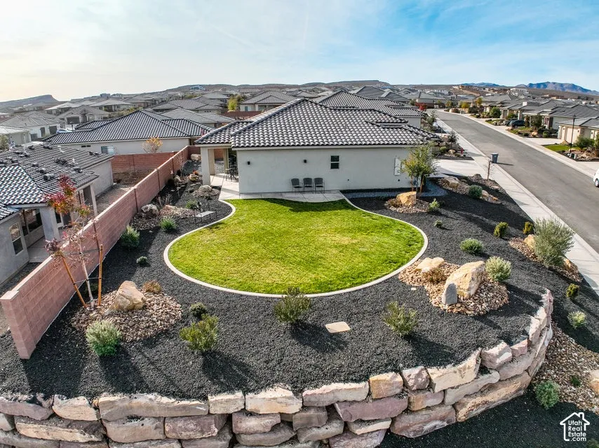 Sloped yard featuring a circular lawn area, stone retaining wall, and dark ground cover