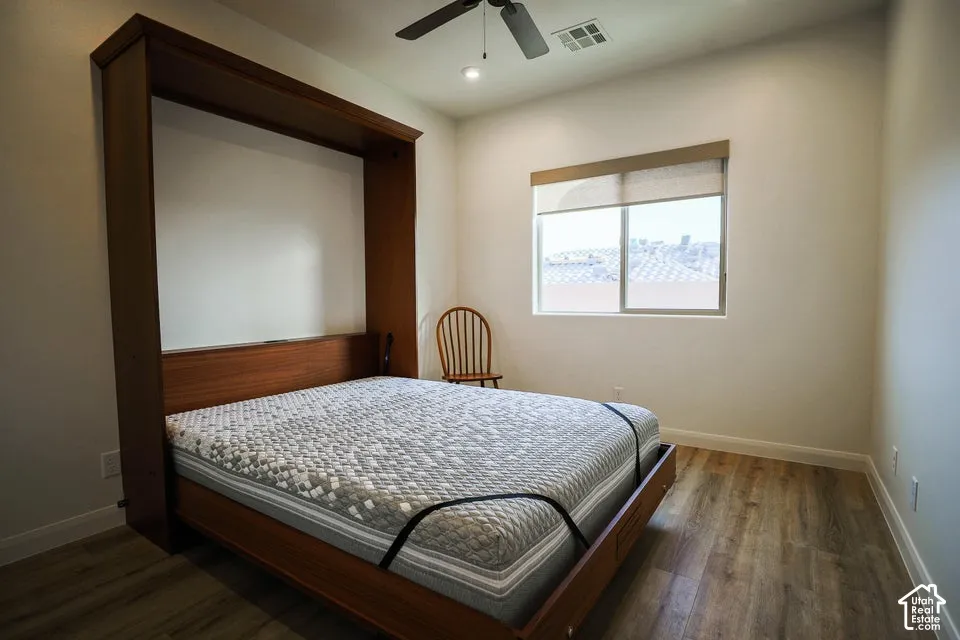 Built-in wooden wall unit, wood-finish flooring, recessed lighting, and a ceiling fan