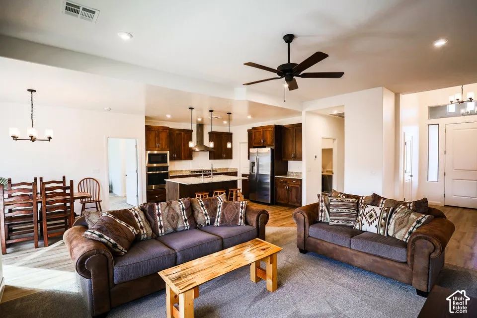 Open-concept living area with a ceiling fan, wood-finish flooring, and recessed lighting