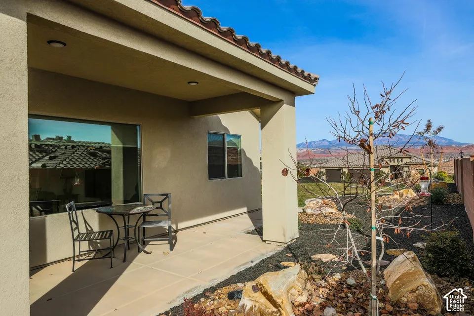Covered patio featuring recessed lighting, a stucco exterior, and a xeriscaped yard with natural rock elements