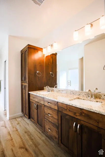 Dual vanity with granite countertops, undermount sinks, and wood cabinetry