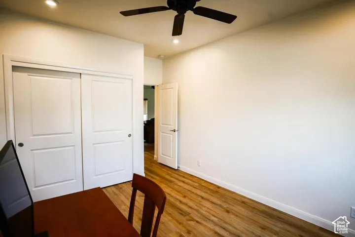 Wood-finish flooring, recessed lighting, ceiling fan, and white doors