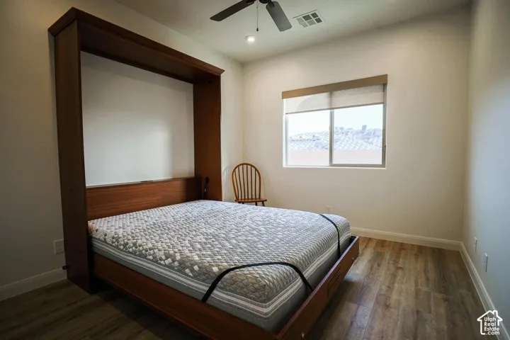 Built-in wooden wall unit, wood-finish flooring, recessed lighting, and a ceiling fan