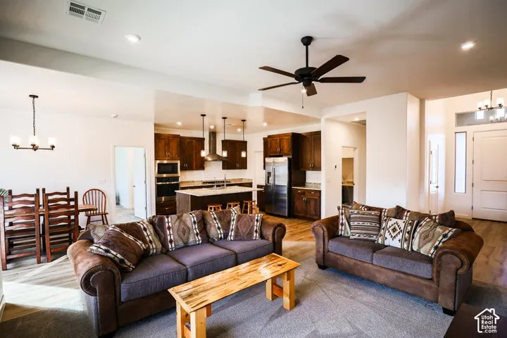 Open-concept living area with a ceiling fan, wood-finish flooring, and recessed lighting