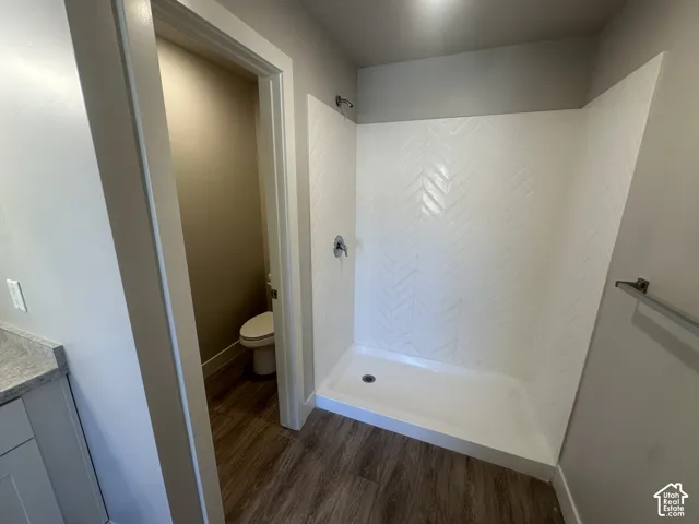 Walk-in shower with herringbone-patterned tile, chrome fixtures, and wood-finish flooring